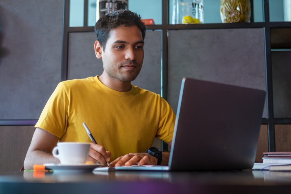 Cheerful Indian man smiling and making notes