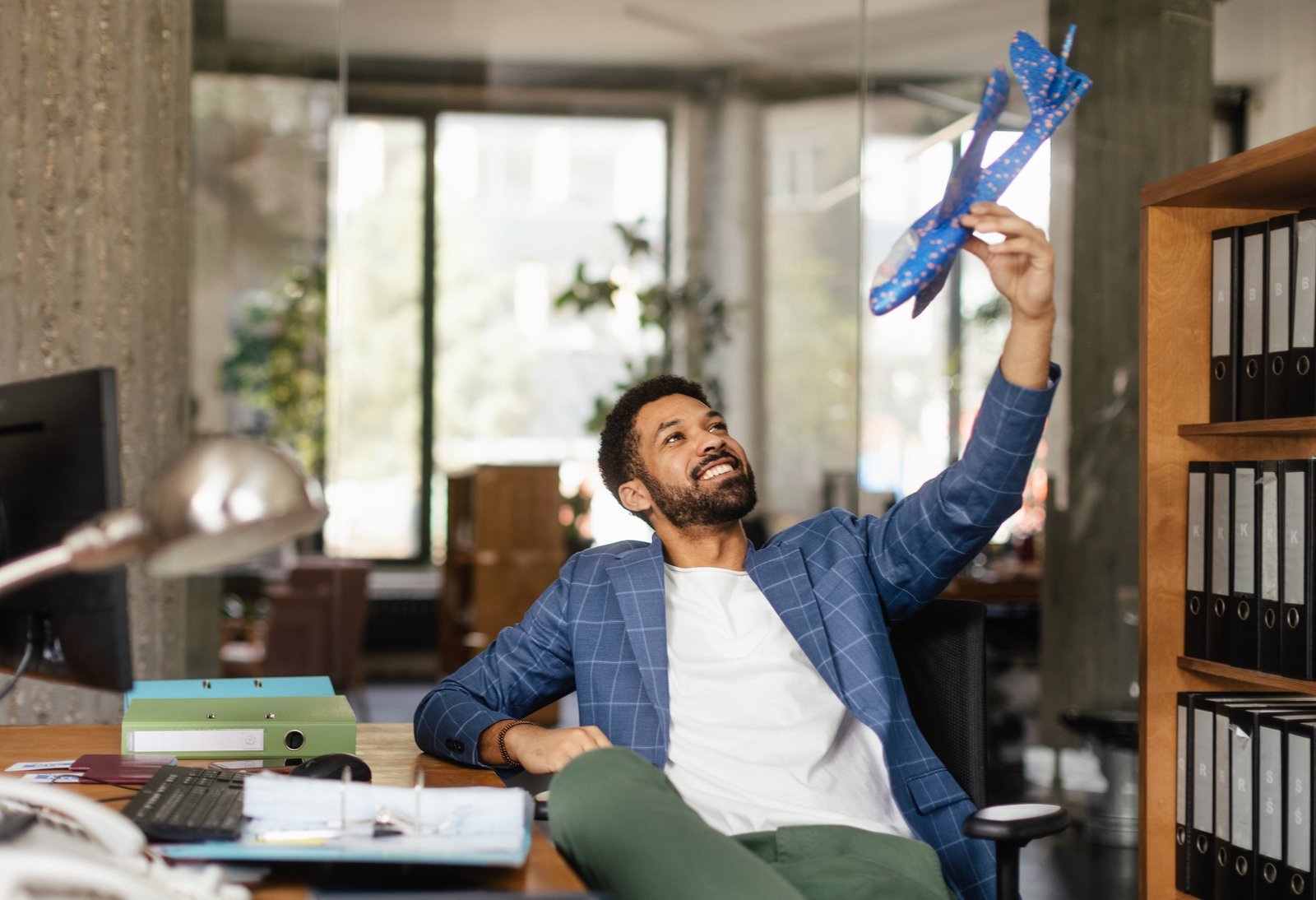 Young happy man holding model of plane in office.